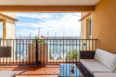 a balcony with a couch and a view of a harbor at Appartement et Studio Le Méditerranée Port Soleil in Gruissan