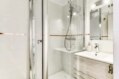 a white bathroom with a shower and a sink at Appartement et Studio Le Méditerranée Port Soleil in Gruissan