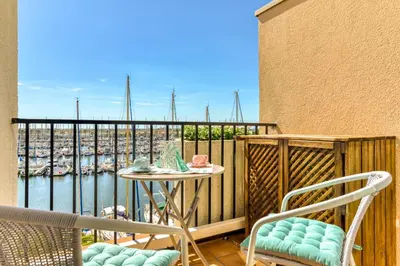 a balcony with a table and chairs and a view of a harbor at Appartement et Studio Le Méditerranée Port Soleil in Gruissan