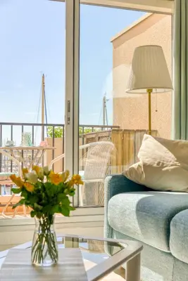 a living room with a couch and a table with a vase of flowers at Appartement et Studio Le Méditerranée Port Soleil in Gruissan