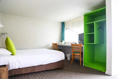 a bedroom with a bed and a desk and a green cabinet at Campanile Narbonne A9/A61 in Narbonne