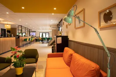 a waiting room with a couch and a lamp at Campanile Narbonne A9/A61 in Narbonne