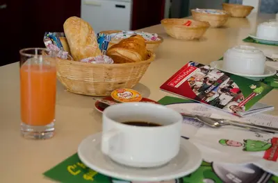 a table with a cup of coffee and a basket of bread at Fasthotel Narbonne in Narbonne