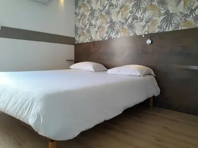 a bedroom with a large bed with white sheets and pillows at Fasthotel Narbonne in Narbonne