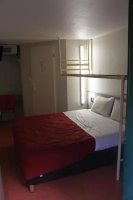 a bedroom with a bed with a red blanket at Hôtel Premiere Classe Pamiers in Pamiers