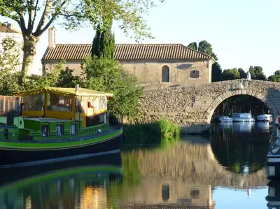 a boat on a river near a bridge at L'Accent d'ici in Le Somail