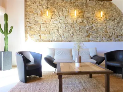 a living room with a table and chairs and a stone wall at L'Accent d'ici in Le Somail