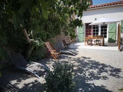 a patio with chairs and a table with an umbrella at Gîte Madeleine in Saint-Nazaire-dʼAude