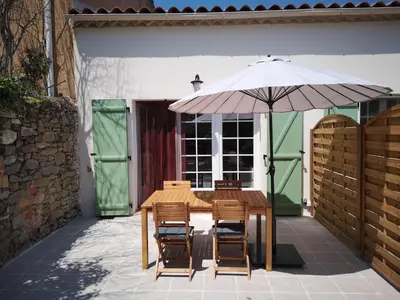 a wooden table and chairs with an umbrella at Gîte Madeleine in Saint-Nazaire-dʼAude