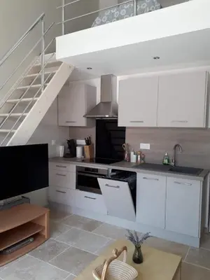 a kitchen with white cabinets and a staircase at Gîte Madeleine in Saint-Nazaire-dʼAude