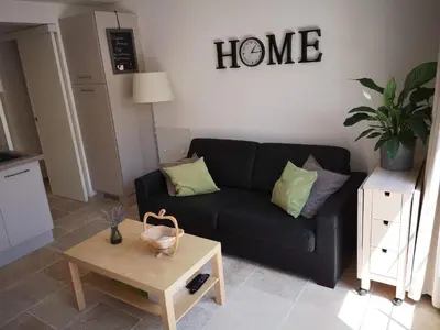 a living room with a black couch and a table at Gîte Madeleine in Saint-Nazaire-dʼAude