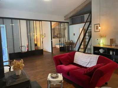 a living room with a red couch and a staircase at Gîte de Genty in Cenne-Monestiès