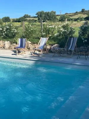 two chairs and a table next to a swimming pool at Gîte de Genty in Cenne-Monestiès