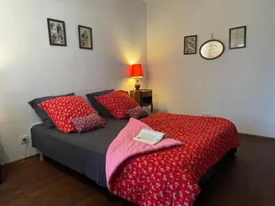 a bedroom with a bed with red pillows and a clock at Gîte de Genty in Cenne-Monestiès