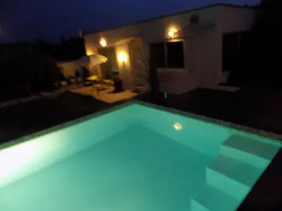 a swimming pool at night with a house at Villa VAYA in Villemoustaussou