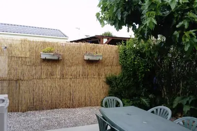 a fence with a table and chairs in a backyard at camping le pavillon in Sigean