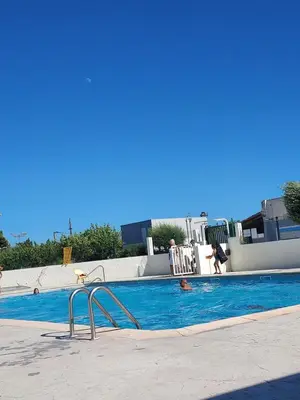 a swimming pool with people in the water at camping le pavillon in Sigean