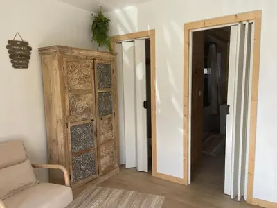 a living room with a wooden door and a chair at Caprice Gruissanais Spa - T2 plage des chalets in Gruissan