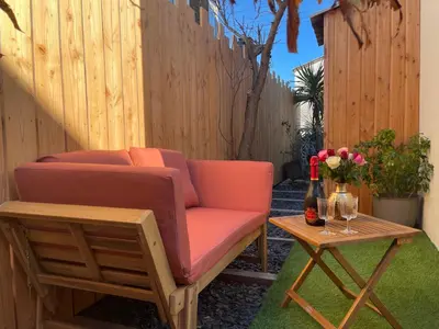 a couch and a table with a bottle of wine at Caprice Gruissanais Spa - T2 plage des chalets in Gruissan