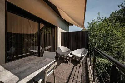 a deck with a table and chairs on a balcony at Hôtel Le Parc - La Table de Franck Putelat in Carcassonne