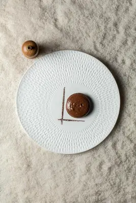 a chocolate donut on a plate on a table at Hôtel Le Parc - La Table de Franck Putelat in Carcassonne
