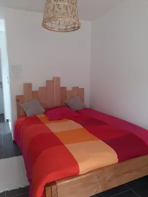 a bedroom with a large bed with a colorful blanket at Chambre privée au coeur d'une pinède dans un quartier résidentiel in Lézignan-Corbières