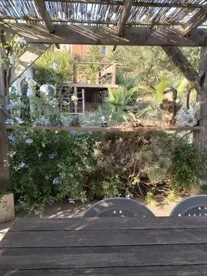 a garden with a wooden table and some plants at Chambre privée au coeur d'une pinède dans un quartier résidentiel in Lézignan-Corbières