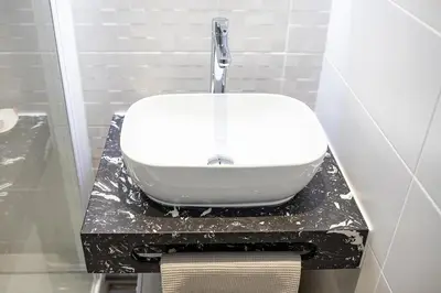 a white sink on a black counter in a bathroom at L'écrin de l'Orb in Cessenon