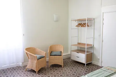 a bedroom with two wicker chairs and a book shelf at L'écrin de l'Orb in Cessenon
