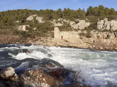a river with rapids and a building in the middle at L'écrin de l'Orb in Cessenon