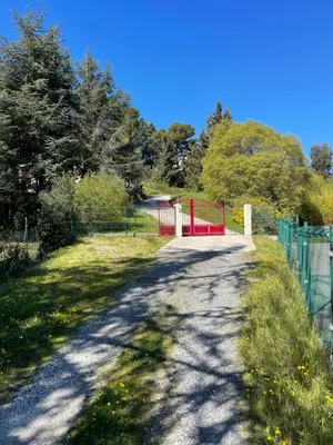 a road with a red gate and a fence at Au Perchoir in Caunes-Minervois