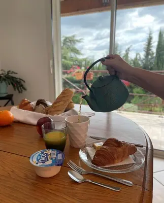 a person holding a teapot over a table with food at Au Perchoir in Caunes-Minervois