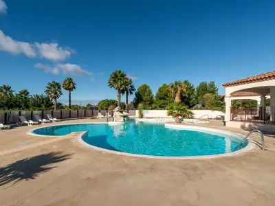 a swimming pool in a resort with palm trees at Vacancéole - Port Minervois, Les Hauts du Lac in Homps