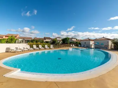 a large swimming pool with lounge chairs in a yard at Vacancéole - Port Minervois, Les Hauts du Lac in Homps