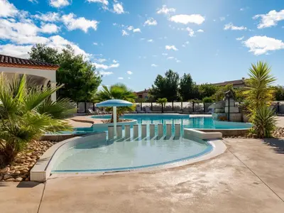a swimming pool with an umbrella and trees at Vacancéole - Port Minervois, Les Hauts du Lac in Homps