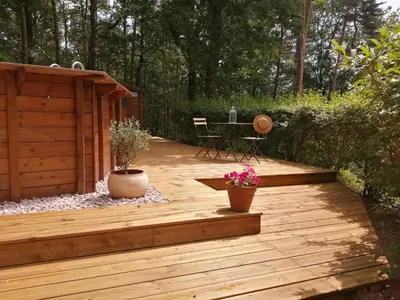 a wooden deck with a table and chairs on it at la fenass in Noailhac