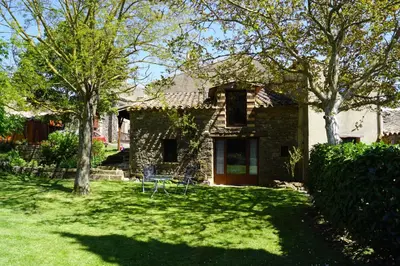 a stone house with a yard with trees at La petite maison dans la prairie in Cassaignes