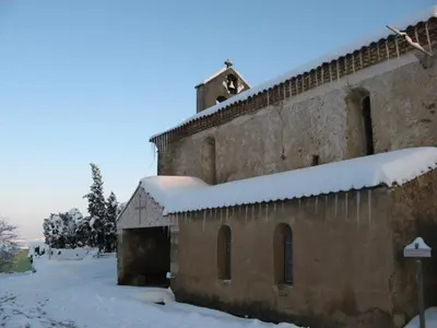 an old building with snow on the roof at La petite maison dans la prairie in Cassaignes