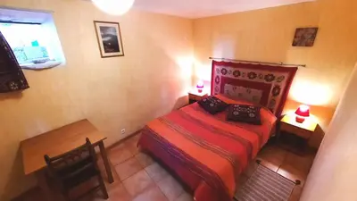 a small bedroom with a red bed and a window at La petite maison dans la prairie in Cassaignes