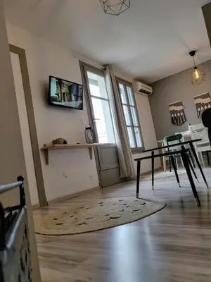 an empty living room with a table and a window at Appartement L'Oliveraie - La Cité plein les yeux in Carcassonne
