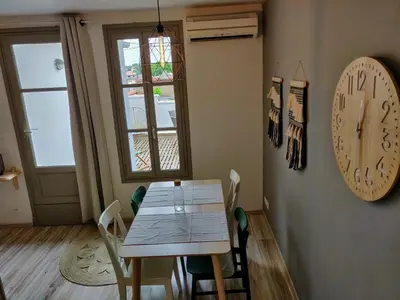 a dining room with a table and a clock on the wall at Appartement L'Oliveraie - La Cité plein les yeux in Carcassonne