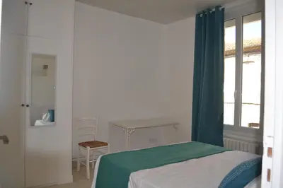 a bedroom with a bed and a table and a window at La Bulle familles Clim, wifi, airport shuttle,tout à pied in Carcassonne