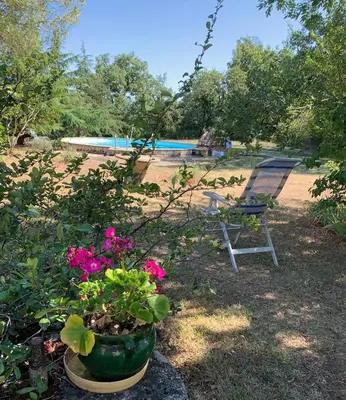 a chair and flowers in a yard with a pool at La Meyssonnié in Damiatte