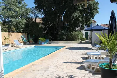 a swimming pool with chairs and an umbrella at Le Jardin du Somail in Le Somail