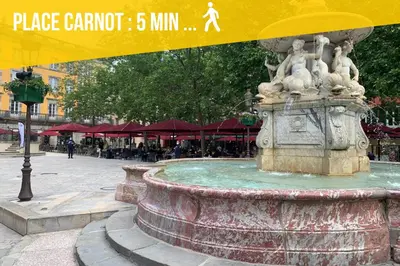 a fountain in the middle of a street with a yellow sign at City'IN Appart in Carcassonne