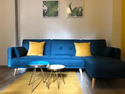 a blue couch with yellow pillows and a table at City'IN Appart in Carcassonne