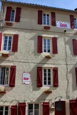 a building with red shutters and a sign on it at Au Coeur de Rennes Chambres d'hôtes in Rennes-les-Bains
