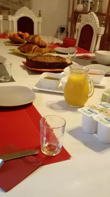 a table with plates and a glass of orange juice at Au Coeur de Rennes Chambres d'hôtes in Rennes-les-Bains