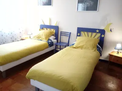 a bedroom with two beds and a chair at Au Coeur de Rennes Chambres d'hôtes in Rennes-les-Bains