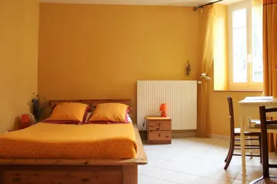 a bedroom with a bed and a table and a window at Au Coeur de Rennes Chambres d'hôtes in Rennes-les-Bains